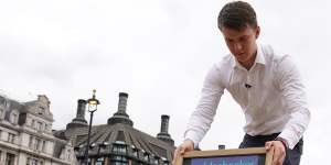 A man puts out a chalkboard with the betting odds for who will replace Boris Johnson as prime minister.