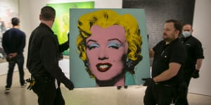 Shot Sage Blue Marilyn being carried into the Christie’s showroom on Sunday. The artwork sold for $US195 million on Monday.