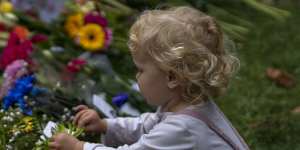 A child touches tributes left for Queen Elizabeth II at the Green Park memorial,where tens of thousands of flowers lay.