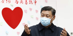 Chinese President Xi Jinping stands next to a poster that reads,'Race against time,Fight the Virus'.