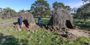 Budj Bim rangers Aaron Morgan and Leigh Boyer stand by replica stone houses in the UNESCO World Heritage-listed Budj Bim cultural landscape.