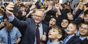 Anthony Albanese poses for a selfie with students during a visit to his old school during the campaign.