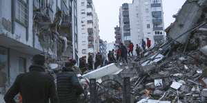 People and rescue teams try to reach trapped residents inside collapsed buildings in Adana,Turkey.