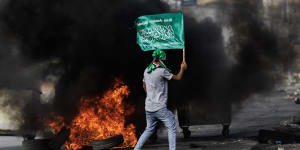 A Palestinian youth carries a Hamas flag amid clashes with Israeli soldiers in the West Bank on October 27.
