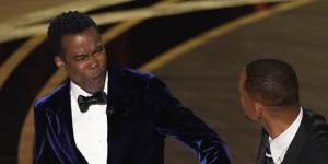Chris Rock,left,reacts after being hit on stage by Will Smith while presenting the award for best documentary feature at the Oscars.