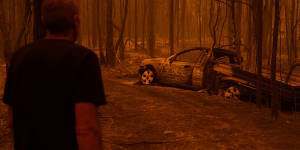 Grant looks at the burnt car he tried to escape in.