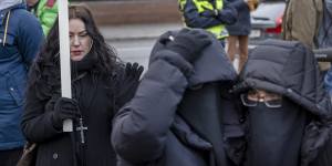 A woman holds up a cross next two Muslim girls while Rasmus Paludan burns the Koran outside the Turkish embassy in Stockholm.