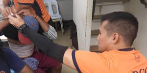 In this photo provided by the Philippine Coast Guard,personnel treat wounded fishermen inside their vessel at the disputed South China Sea on Saturday.