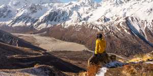 A trekker sitting on top of Kyanjo Ri view point and enjoying landscape of Langtang valley. Himalaya mountains range in Nepal,Asia Cover:Nepal:trekking a decade on from the earthquake text by Andrew Bain