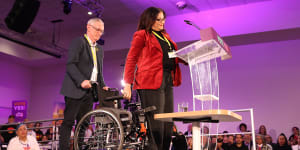 Tanya Hosch rises from her wheelchair to speak.