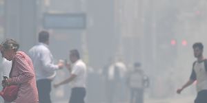 Pedestrians cross a hazy George Street as smoke haze blankets Sydney on Tuesday.