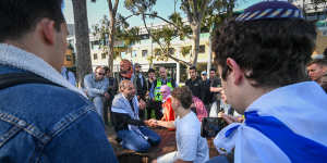 Supporters of Israel and Palestine shake hands after they sit down to discuss the war in Gaza at the Monash encampment.