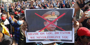 A protester holds a placard with a defaced image of Myanmar military commander-in-chief Senior General Min Aung Hlaing.