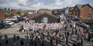 Crowds gather at the newly repaired Marcus Rashford mural in Manchester.