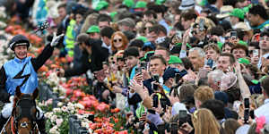 Jamie Melham throws her race goggles into the crowd after winning the Melbourne Cup on Half Yours.