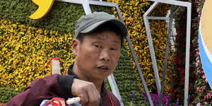 A man selling Chinese drums walks past a decoration promoting the upcoming Belt and Road Forum in Beijing.