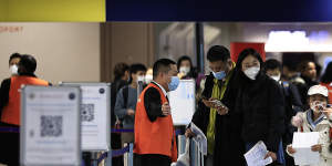 Passengers arriving from China this week wait in front of a COVID-19 testing area set at Charles de Gaulle airport. Australia will follow 10 other nations,including France,in screening passengers from China for COVID.
