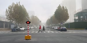 Pedestrians cross a near deserted road in Beijing,China,on Friday.