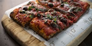 Puttanesca pizza a taglio is all crisp crust and salty,savoury topping of tomato sugo,anchovy,olives and basil.