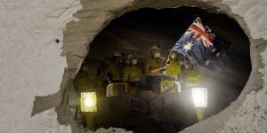 A worker on one of the two roadheaders waves the Australian flag moments after smashing through sandstone connecting two sections of the M4-M5 Link.