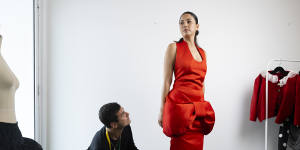 Designer Jordan Dalah with his dress for model Jessica Gomes to wear in the Mumm marquee at the Cup carnival.