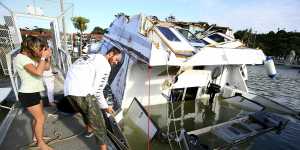 A couple look at a damaged boat in a marina at Tutukaka,New Zealand,on Sunday.