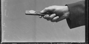 The hand of a spinner holding a two-up kip in Reservoir Street,Sydney,1930.