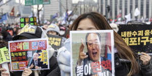 A demonstrator holds a placard featuring impeached South Korean President Yoon Suk Yeol.