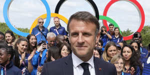 French President Emmanuel Macron poses with French athletes as he visits the Olympic Village on Monday.