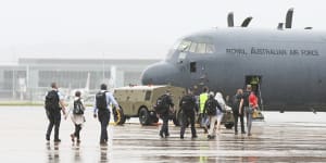 Australian Federal Police personnel board an RAAF C-130 Hercules bound for the Solomon Islands,at RAAF Fairbairn in Canberra on Friday November 26,2021. 