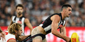 Scott Pendlebury of the Magpies passes is tackled by James Rowbottom of the Swans.