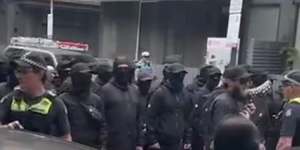 Neo-Nazis dressed in black and wearing balaclavas at the refugee protest.