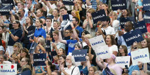 Democrats hold up signs in support of Vice President Kamala Harris as she campaigns for president.