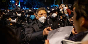 A local official speaks with a demonstrator holding a blank sign during a protest in Beijing.