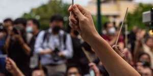 Anti-government protesters wave chopsticks as makeshift wands to"Cast the Patronus Charm to Protect Democracy"in Bangkok on Monday.