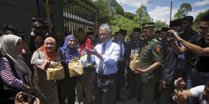 Malaysia's King Sultan Abdullah Sultan Ahmad Shah,centre,hands out food parcels to journalists camped outside the palace following the resignation of Prime Minister Mahathir Mohamad in Kuala Lumpur on Tuesday.