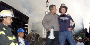 George W. Bush stands with firefighter Bob Beckwith on a burnt fire truck in front of the World Trade Centre during a tour of the devastation on September 14,2001.