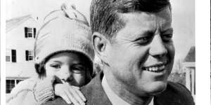 Caroline Kennedy,almost three,peeps over her father John F. Kennedy’s shoulder. 