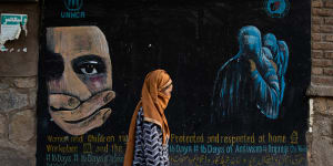 A woman walks past a mural calling for women and children’s rights in Afghanistan.