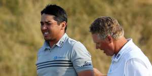 Jason Day of Australia walks off the 18th green with his caddie Colin Swatton after shooting a two-under par 68 during the third round of the US Open Championship.