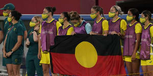 The Matildas line up behind the Aboriginal flag in Tokyo.