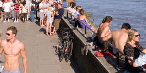 Sun’s out,guns out:People relax alongside the Thames in a rare show of sunshine.