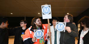 Thomas Marynissen,left,Wesley Fung,and Logan Newboult-Kosztyo,holding Metro signs,at Sydenham station.