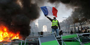 A demonstrator waves the French flag near a burning barricade on the Champs-Elysees on Saturday.