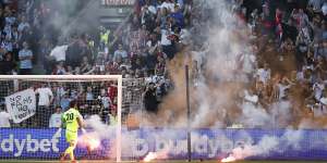 Paul Izzo of Melbourne Victory removes a flare from the pitch after a Melbourne City goal.