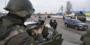 A Ukrainian National guard soldier,left,holds his weapon ready as he guards the mobile checkpoint with the Ukrainian Security Service agents and police officers in Kharkiv,Ukraine.