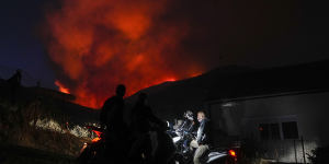 Men on motorcycles watch a fire at Penteli,Greece in July.