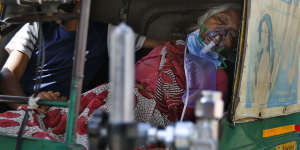 A coronavirus patient wearing an oxygen mask waits inside an auto rickshaw to be admitted to a dedicated COVID-19 government hospital in Ahmedabad,India,on Saturday.