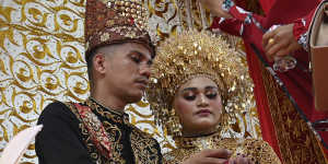 A newly-wedded couple sits on a dais while receiving blessings from family members during a traditional wedding in Banda Aceh,Indonesia.