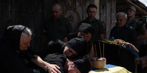 Maryna Hrynchuk cries over her husband’s coffin. He was killed in the Luhansk region.